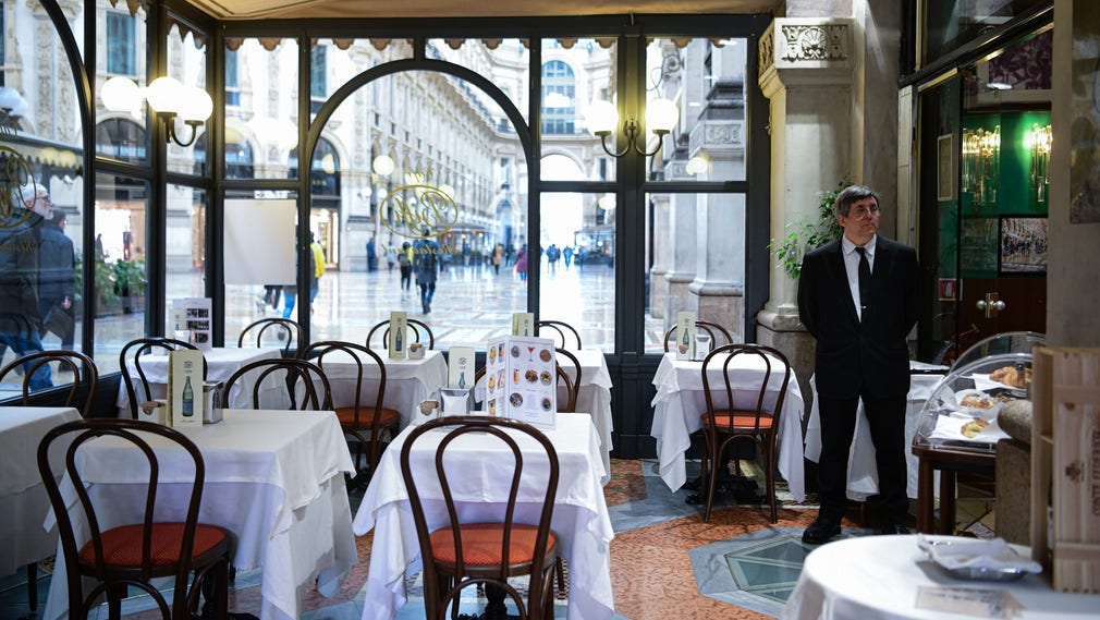 Tomt på gäster. En kypare väntar på kunder i en restaurang i centrala Milano.