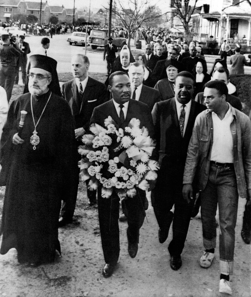 Medborgarrättskämpen Martin Luther King bär en blomsterkrans under minnesceremonin för James Reeb som mördades av en mobb 1965.