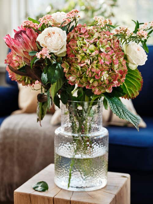 Glasvas Konstfull, 249 kronor, Ikea. Buketten består av hortensia, rosor, bäreukalyptus, protea och korallranka.